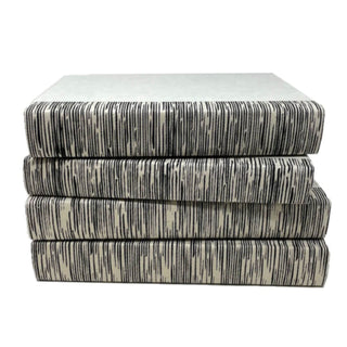 Decorative books with striated black design on neutral background. 