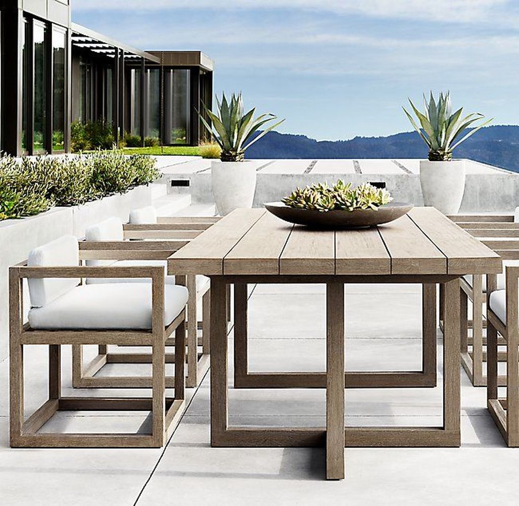 Angled view of grey wooden outdoor dining table with tapered legs.